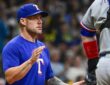 Texas Rangers manager Skip Schumaker raises a hand to signal for a relief pitcher as his catcher waits.