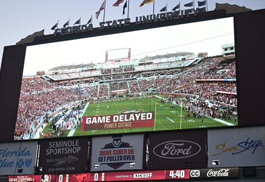 A stadium videoboard reads Game Delayed, Power Outage above a kickoff countdown before SMU plays Florida State.