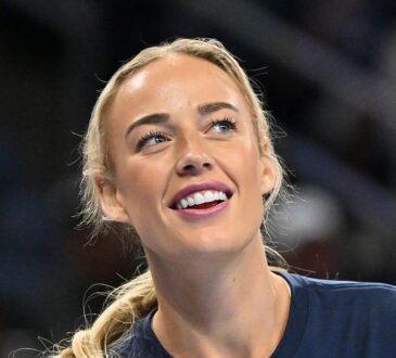 Indiana Fever guard Sophie Cunningham smiles and looks upward while warming up in a navy T-shirt.