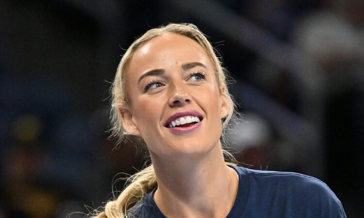 Indiana Fever guard Sophie Cunningham smiles and looks upward while warming up in a navy T-shirt.