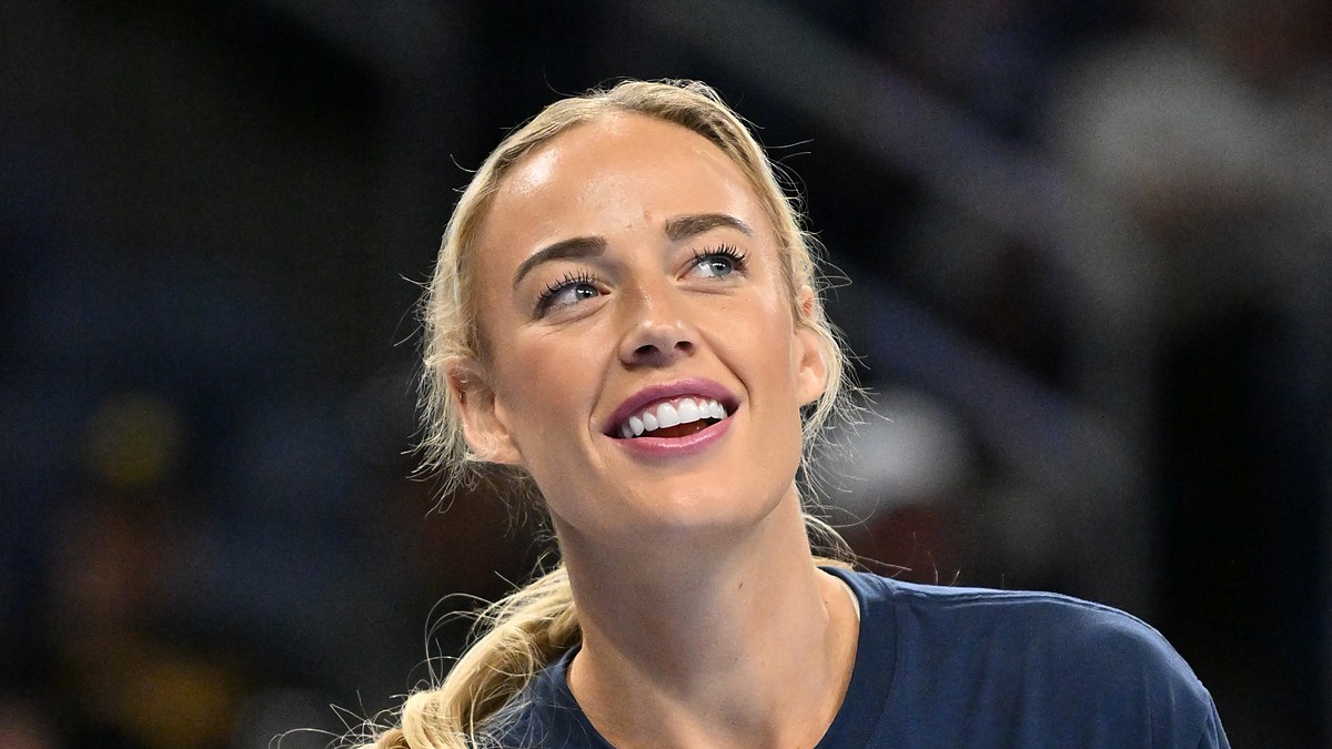 Indiana Fever guard Sophie Cunningham smiles and looks upward while warming up in a navy T-shirt.