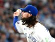 Toronto Blue Jays relief pitcher Spencer Arrighetti, his long hair flowing from under his cap, delivers a pitch.