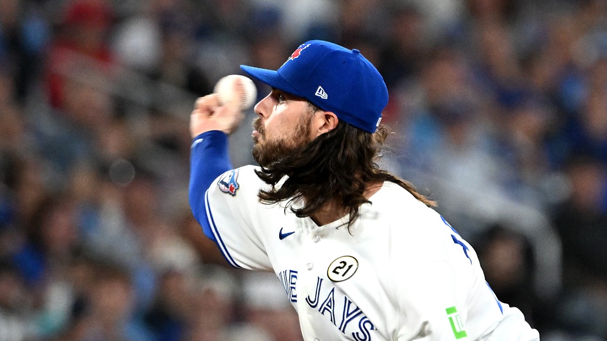 Toronto Blue Jays relief pitcher Spencer Arrighetti, his long hair flowing from under his cap, delivers a pitch.