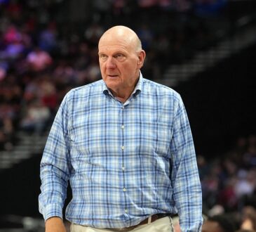Clippers owner Steve Ballmer stands courtside in a plaid shirt watching the game against the Spurs.