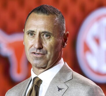 Texas Longhorns head coach Steve Sarkisian speaks in front of a Longhorns and SEC backdrop at media days.