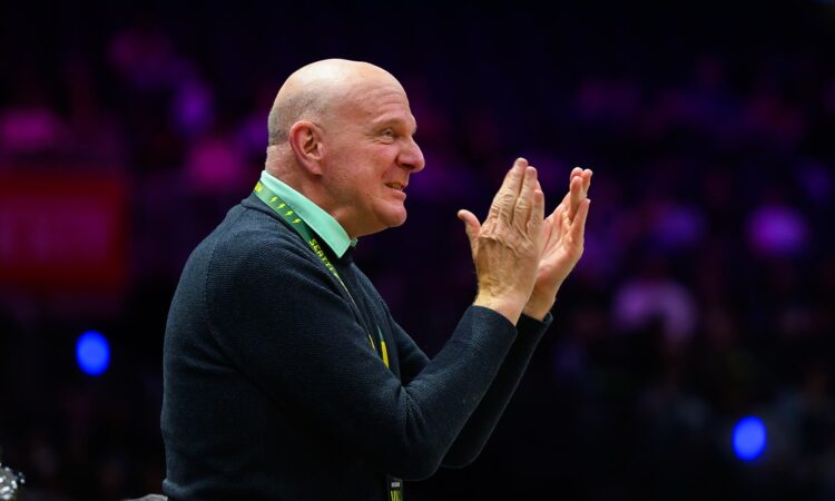 Los Angeles Clippers owner Steven Ballmer smiles and claps while wearing a Seattle Storm VIP lanyard.
