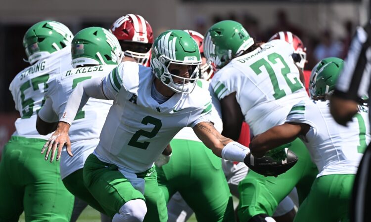 North Texas Mean Green quarterback Tayven Jackson, No. 2, extends the ball on a handoff behind his line.