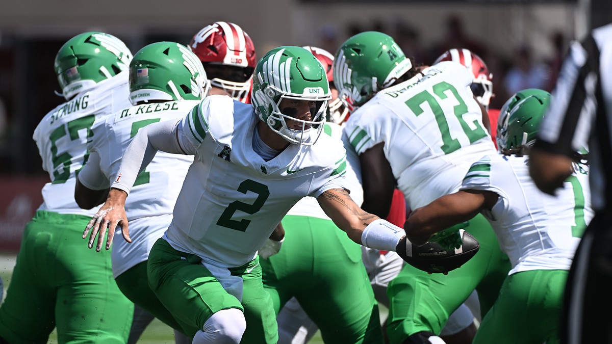North Texas Mean Green quarterback Tayven Jackson, No. 2, extends the ball on a handoff behind his line.