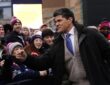 Former New England Patriot Tedy Bruschi bumps fists with fans along a barricade before a playoff game.