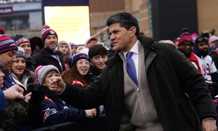 Former New England Patriot Tedy Bruschi bumps fists with fans along a barricade before a playoff game.
