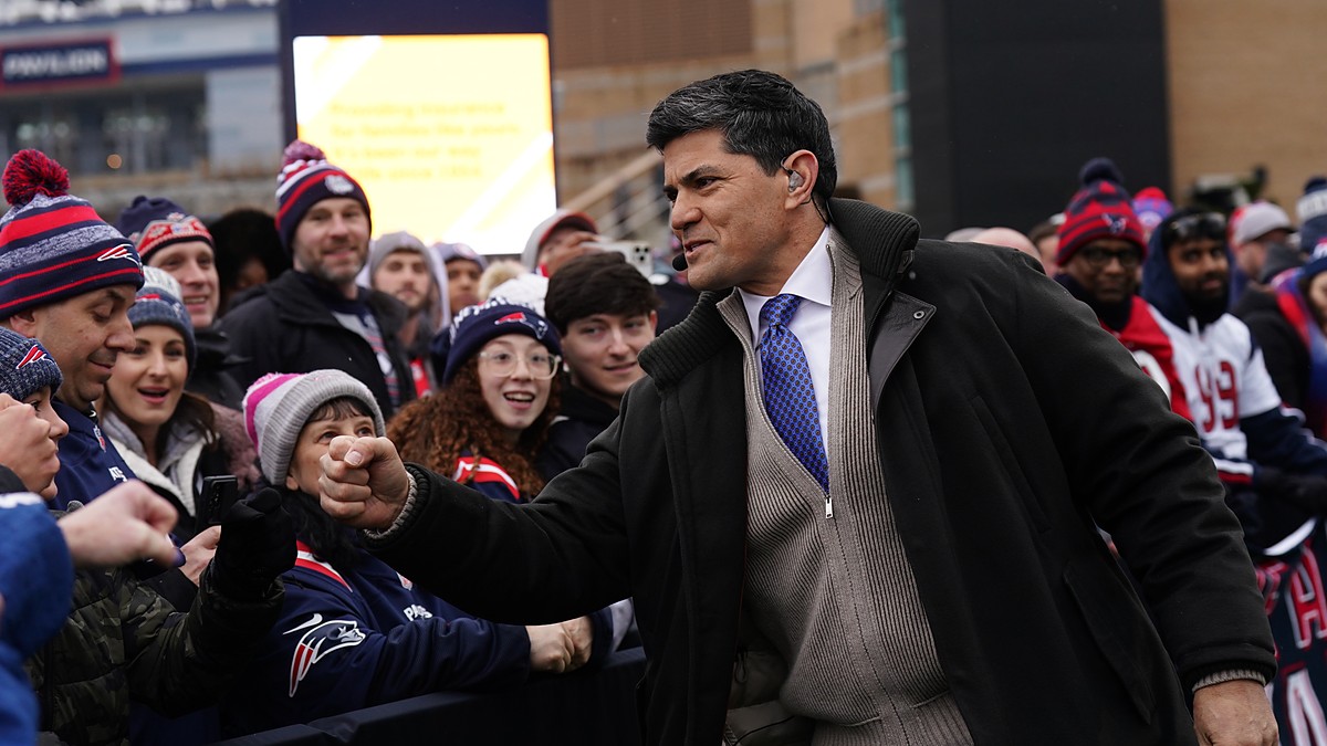 Former New England Patriot Tedy Bruschi bumps fists with fans along a barricade before a playoff game.