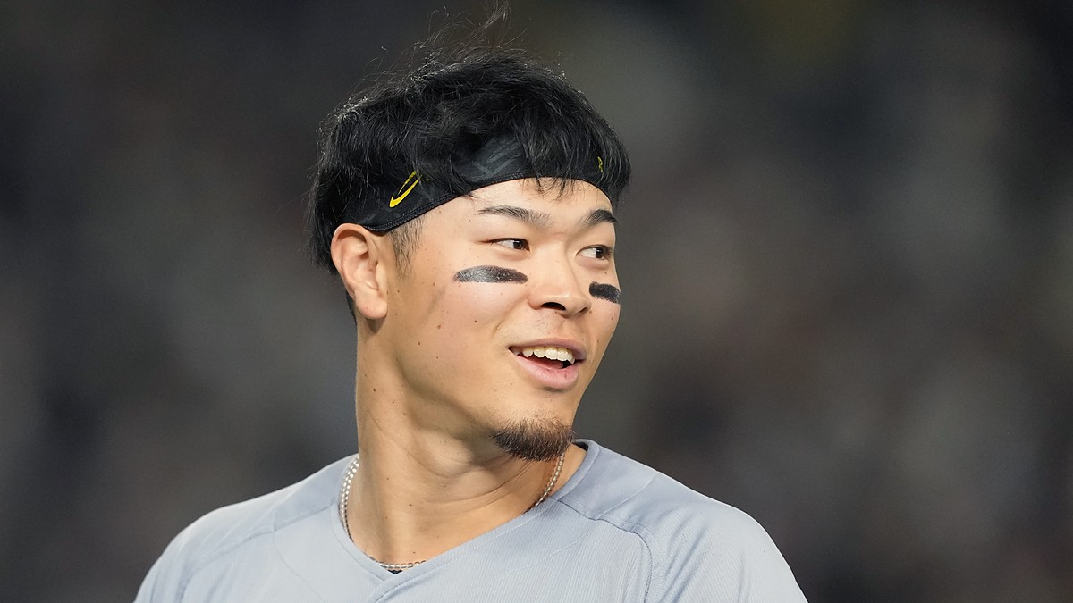 Hanshin Tigers right fielder Teruaki Sato, wearing a black headband and eye black, smiles and looks to his left.