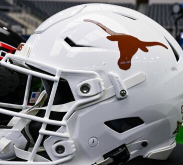 A white Texas Longhorns football helmet sits on a table with a Texas Tech helmet behind it at AT&T Stadium.