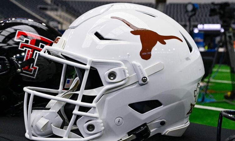A white Texas Longhorns football helmet sits on a table with a Texas Tech helmet behind it at AT&T Stadium.