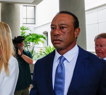 Tiger Woods in a dark suit walks from a courthouse alongside Vanessa Trump after a court appearance.