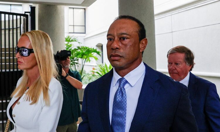 Tiger Woods in a dark suit walks from a courthouse alongside Vanessa Trump after a court appearance.
