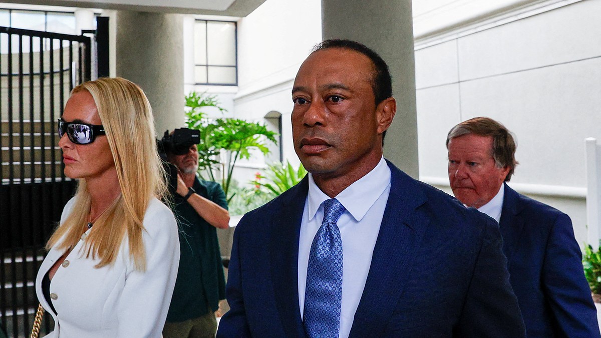 Tiger Woods in a dark suit walks from a courthouse alongside Vanessa Trump after a court appearance.
