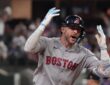 Boston Red Sox shortstop Trevor Story throws both hands up and shouts as he rounds the bases after a home run.