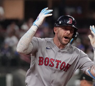 Boston Red Sox shortstop Trevor Story throws both hands up and shouts as he rounds the bases after a home run.