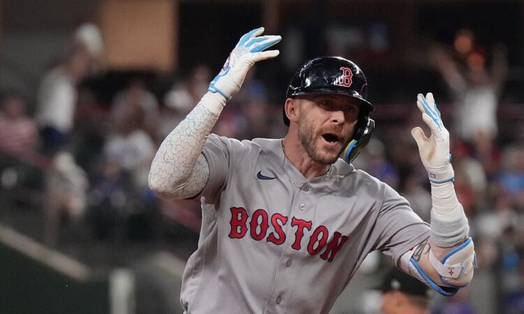 Boston Red Sox shortstop Trevor Story throws both hands up and shouts as he rounds the bases after a home run.