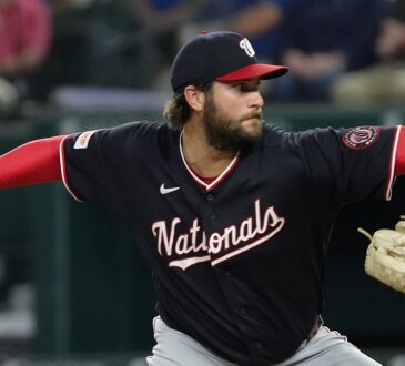 Washington Nationals pitcher Trevor Williams reaches back to deliver in his navy road uniform at Globe Life Field.