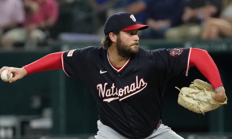 Washington Nationals pitcher Trevor Williams reaches back to deliver in his navy road uniform at Globe Life Field.