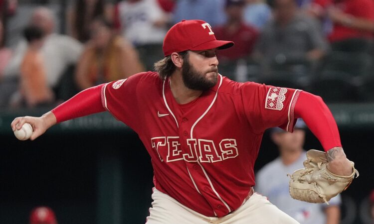 Texas Rangers pitcher Trevor Williams, in a red Tejas jersey, rears back to throw a pitch from the mound.