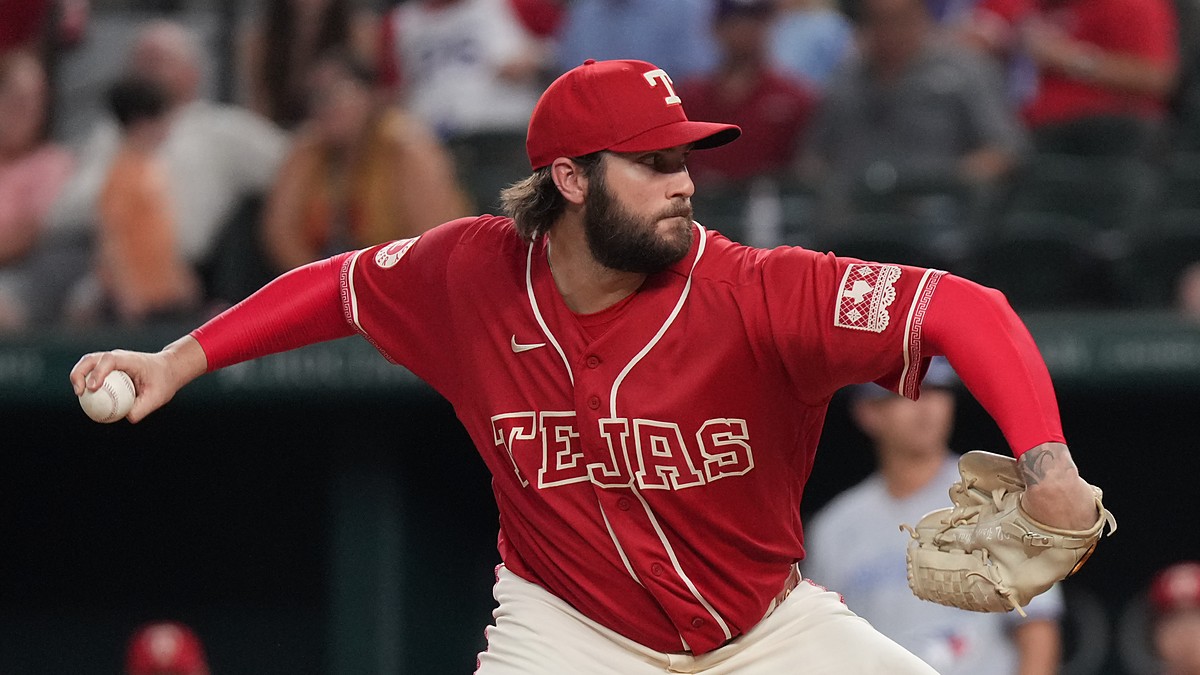 Texas Rangers pitcher Trevor Williams, in a red Tejas jersey, rears back to throw a pitch from the mound.