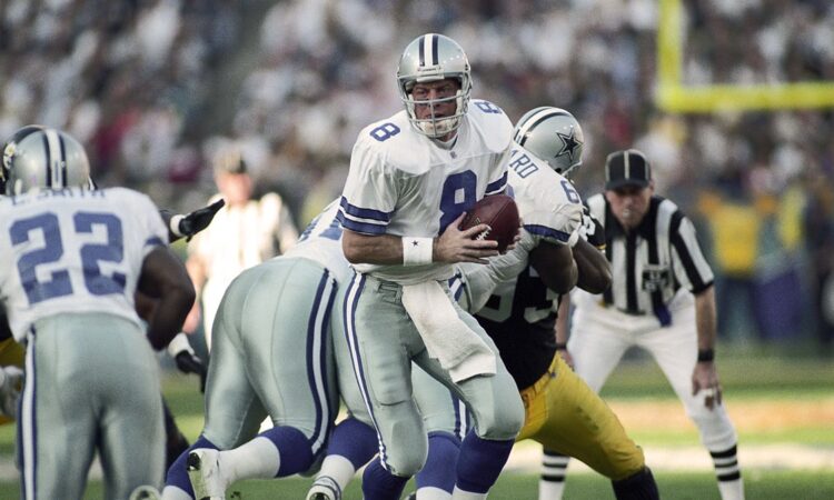 Dallas Cowboys quarterback Troy Aikman turns with the ball to hand off to running back Emmitt Smith against the Steelers.