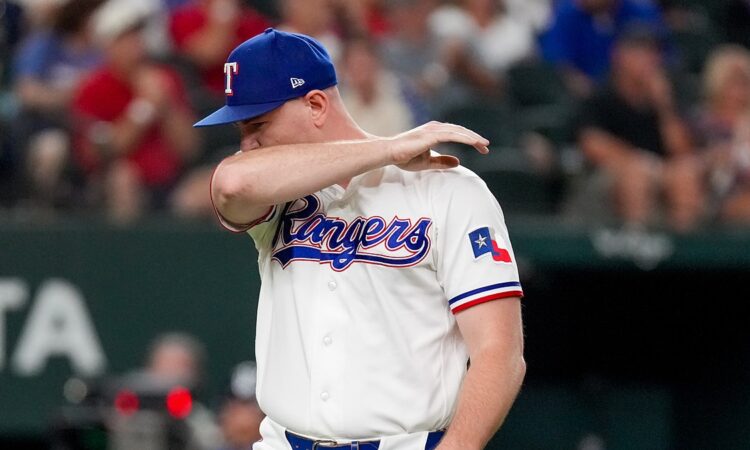 Texas Rangers relief pitcher Tyler Alexander wipes his face with his arm as he walks off the field.