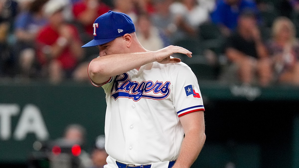 Texas Rangers relief pitcher Tyler Alexander wipes his face with his arm as he walks off the field.