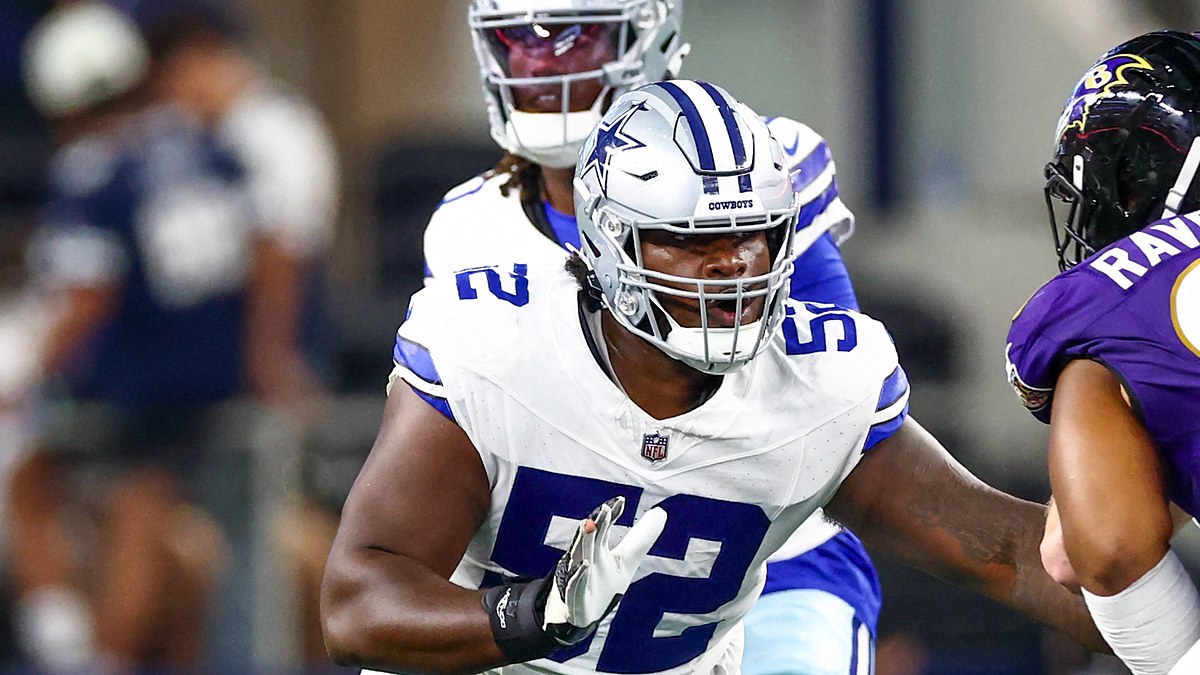 Dallas Cowboys guard Tyler Booker sets up to block with the quarterback standing behind him.