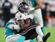 Falcons running back Tyler Goodson holds the ball as Dolphins safety Lonnie Johnson Jr. drags him down.
