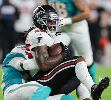 Falcons running back Tyler Goodson holds the ball as Dolphins safety Lonnie Johnson Jr. drags him down.