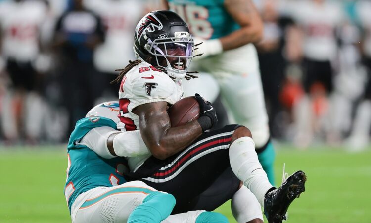 Falcons running back Tyler Goodson holds the ball as Dolphins safety Lonnie Johnson Jr. drags him down.