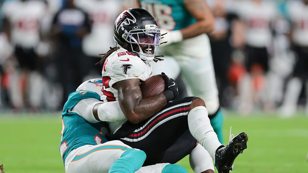 Falcons running back Tyler Goodson holds the ball as Dolphins safety Lonnie Johnson Jr. drags him down.