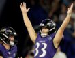 Baltimore Ravens kicker Tyler Loop raises both arms overhead as a teammate reaches toward him.
