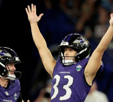 Baltimore Ravens kicker Tyler Loop raises both arms overhead as a teammate reaches toward him.