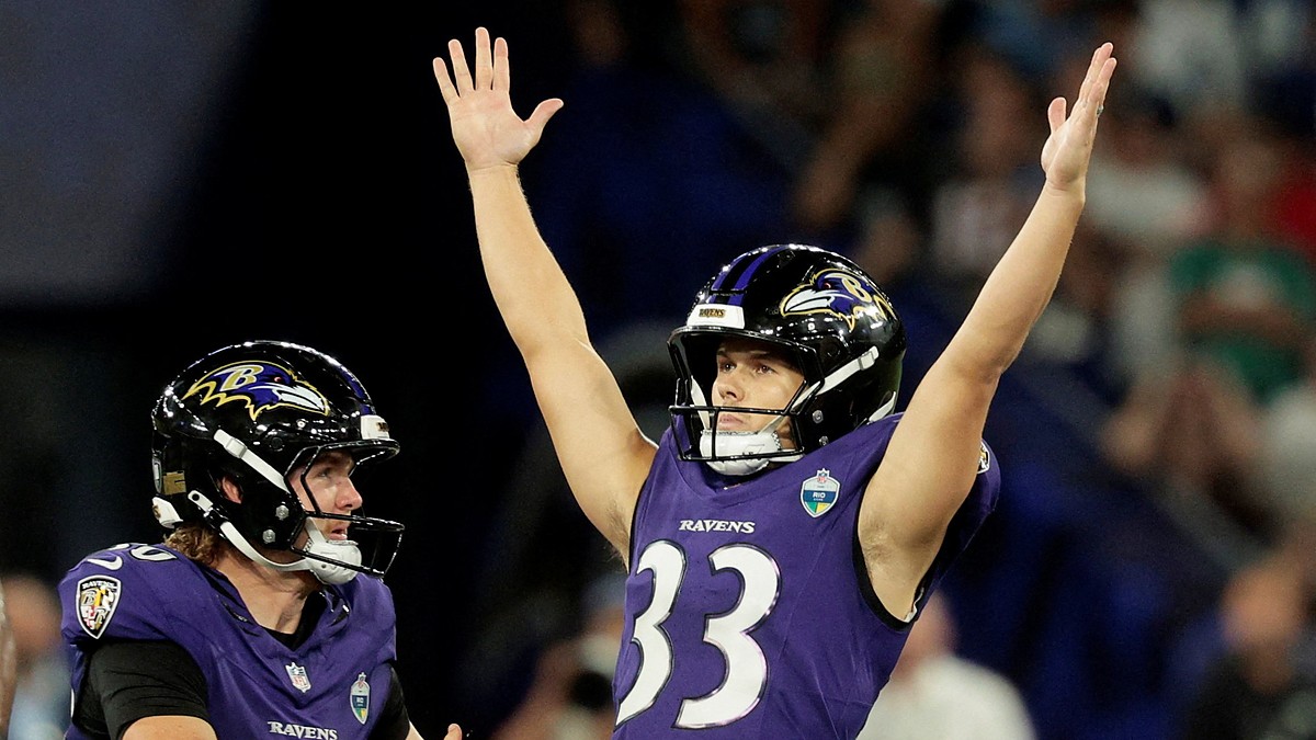 Baltimore Ravens kicker Tyler Loop raises both arms overhead as a teammate reaches toward him.