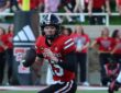 Texas Tech Red Raiders quarterback Will Hammond, No. 15, holds the ball and scans downfield while scrambling.