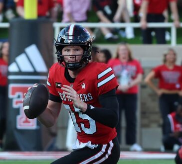 Texas Tech Red Raiders quarterback Will Hammond, No. 15, holds the ball and scans downfield while scrambling.