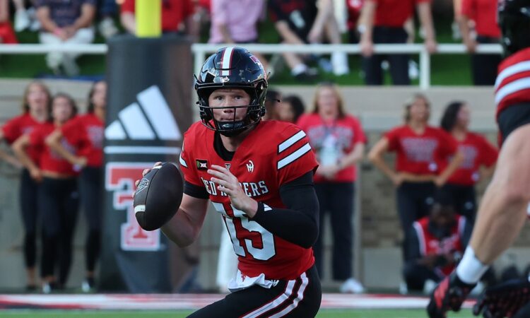 Texas Tech Red Raiders quarterback Will Hammond, No. 15, holds the ball and scans downfield while scrambling.