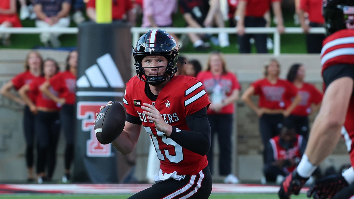 Texas Tech Red Raiders quarterback Will Hammond, No. 15, holds the ball and scans downfield while scrambling.