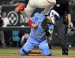 Toronto Blue Jays catcher Alejandro Kirk braces on his knees as Texas Rangers left fielder Wyatt Langford leaps over him at the plate.