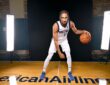 Dallas Mavericks guard Zaccharie Risacher crouches in a dribbling pose with a basketball in front of a black studio backdrop.
