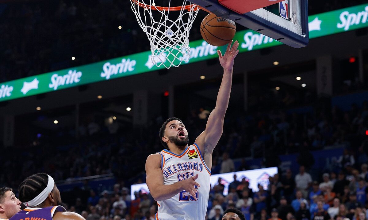 Oklahoma City Thunder guard Ajay Mitchell reaches for a layup as Phoenix Suns defenders look up from below the rim.