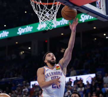 Oklahoma City Thunder guard Ajay Mitchell reaches for a layup as Phoenix Suns defenders look up from below the rim.