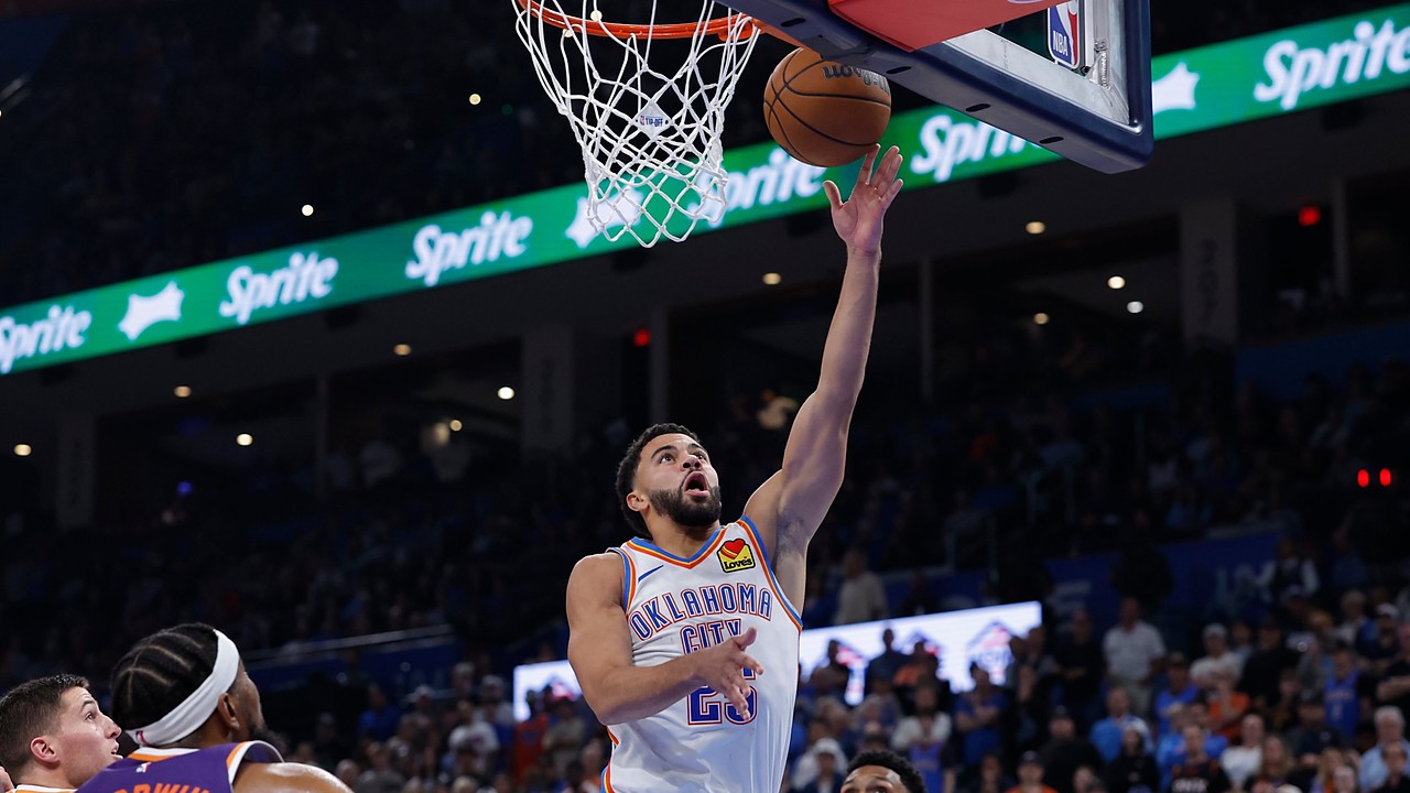 Oklahoma City Thunder guard Ajay Mitchell reaches for a layup as Phoenix Suns defenders look up from below the rim.