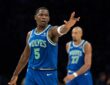 Minnesota Timberwolves guard Anthony Edwards holds up three fingers on each hand after making a shot, with teammates behind him.