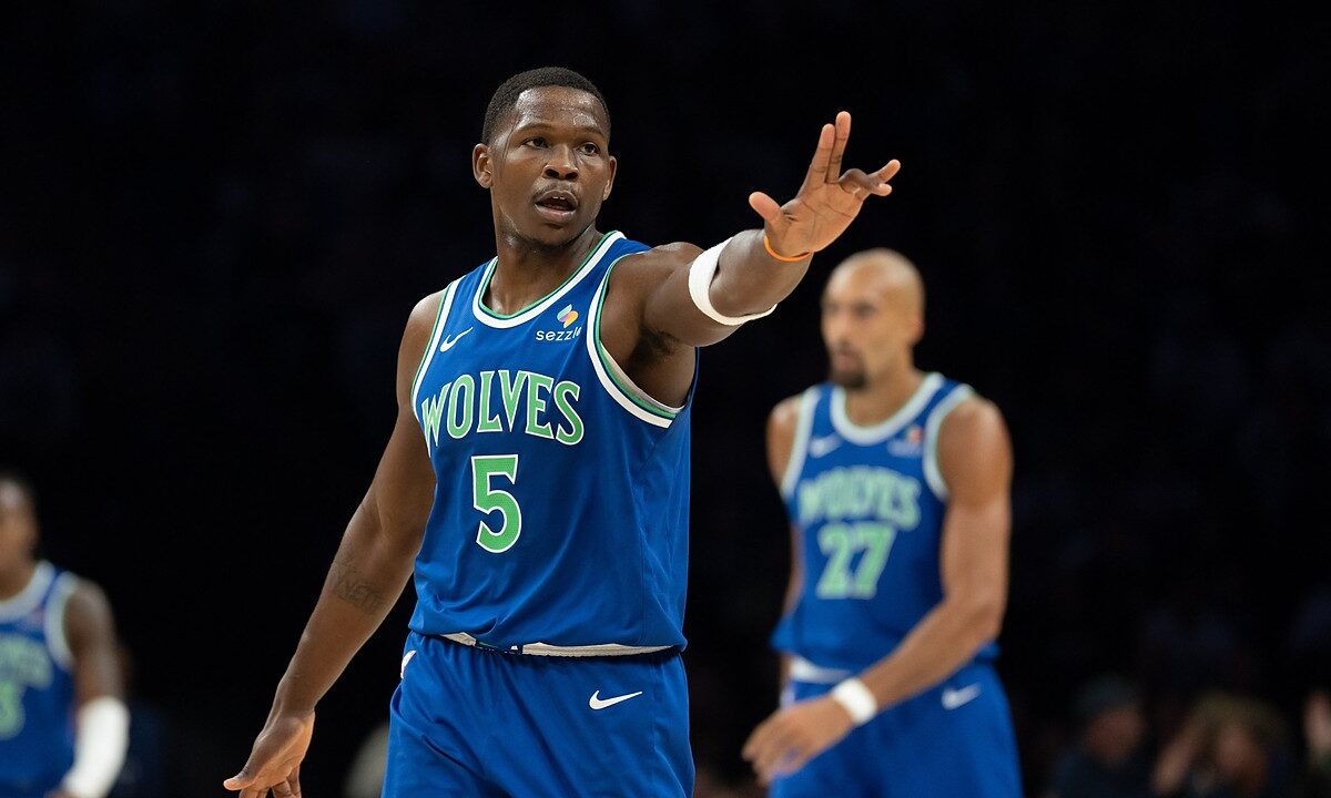Minnesota Timberwolves guard Anthony Edwards holds up three fingers on each hand after making a shot, with teammates behind him.